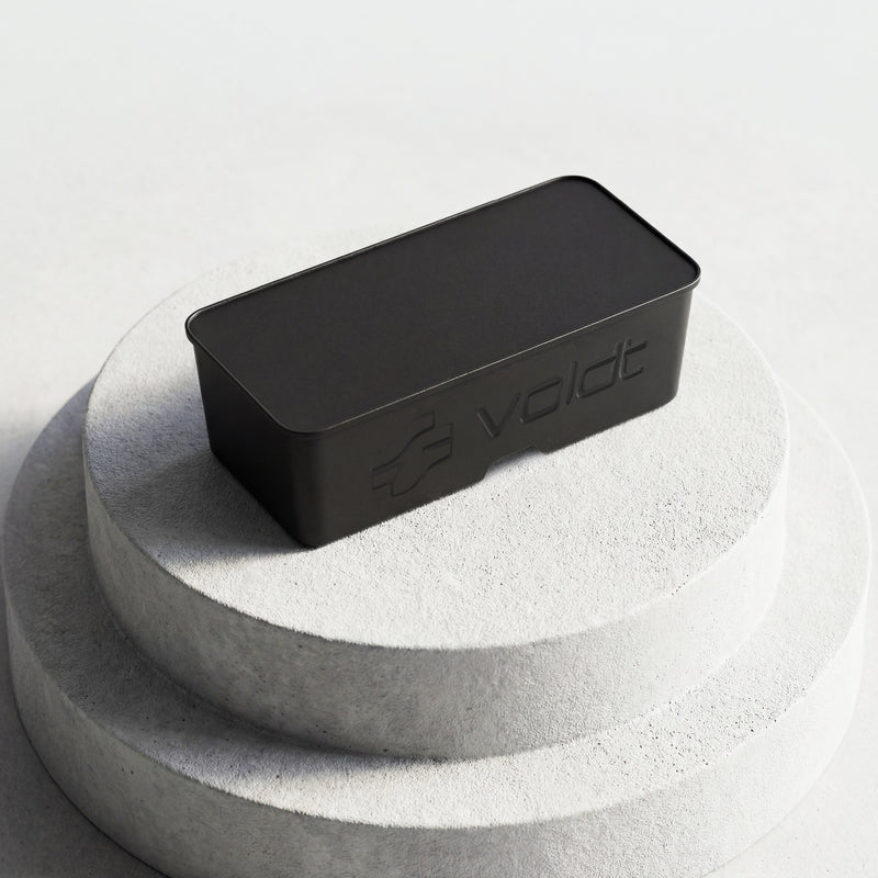 Closed black Voldt® EV cable storage box displayed on a stone plinth